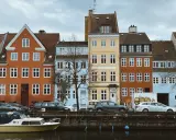 Kolorowe kamienice nad kanałem, łodzie i samochody – typowe kopenhaga atrakcje.
