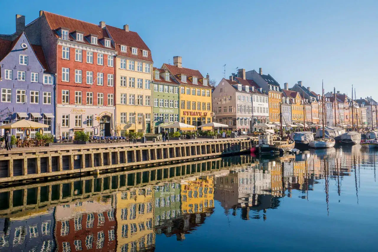 Kolorowe kamienice nad kanałem Nyhavn, jedna z głównych kopenhaga atrakcje, odbijają się w spokojnej wodzie.